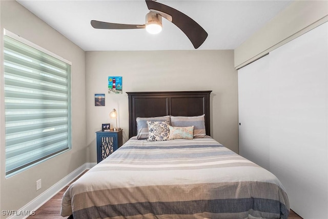 bedroom with baseboards, multiple windows, a ceiling fan, and dark wood-style flooring