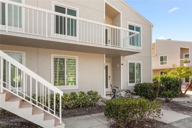 exterior space featuring stairway, a balcony, and stucco siding