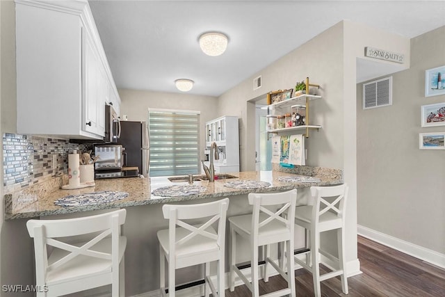 kitchen featuring appliances with stainless steel finishes, white cabinetry, a sink, and a kitchen breakfast bar