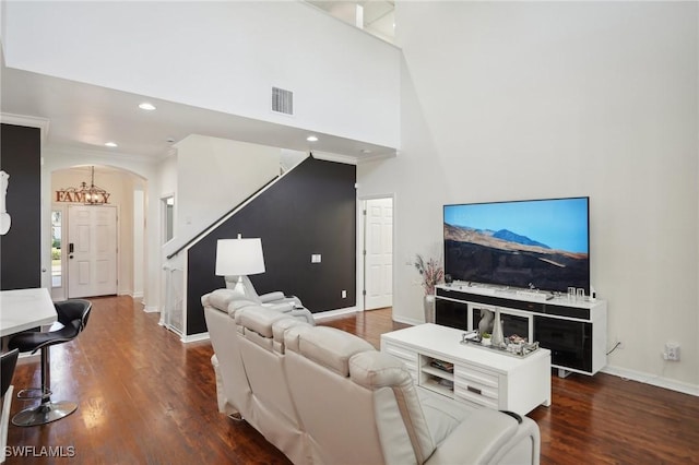 living room with a towering ceiling, visible vents, arched walkways, and wood finished floors