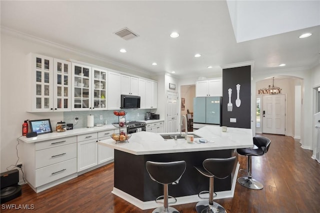 kitchen featuring arched walkways, white cabinets, glass insert cabinets, appliances with stainless steel finishes, and a sink