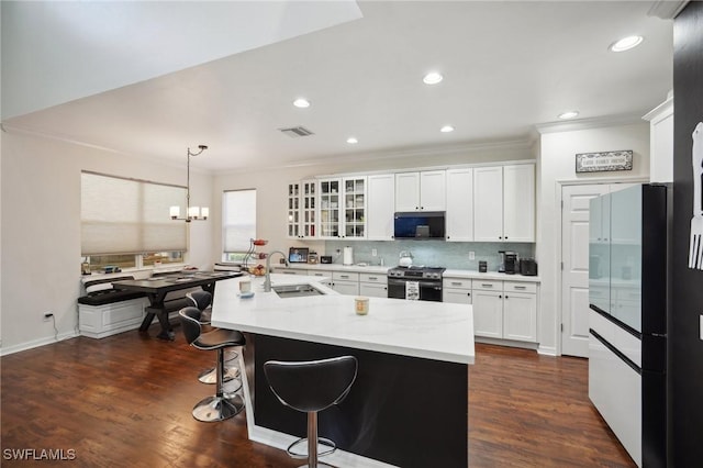 kitchen with white cabinets, glass insert cabinets, stainless steel range with gas cooktop, black microwave, and a sink