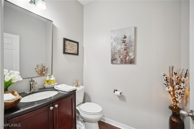 bathroom featuring toilet, baseboards, and vanity