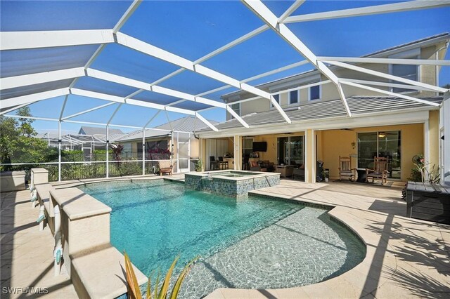 view of swimming pool featuring glass enclosure, a pool with connected hot tub, and a patio