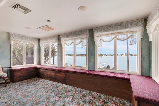 unfurnished sunroom with visible vents and a water view