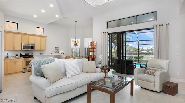 living area featuring light tile patterned floors, baseboards, an inviting chandelier, a high ceiling, and recessed lighting