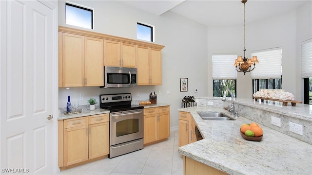 8342 Provencia Ct, Fort Myers, FL 33912 - kitchen with stainless steel appliances, light brown cabinets, a high ceiling, light tile patterned floors, and a chandelier
