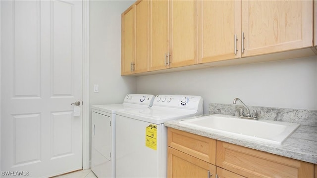 clothes washing area with cabinet space, a sink, and washing machine and clothes dryer