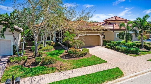 view of front of house featuring decorative driveway, a tile roof, an attached garage, and stucco siding