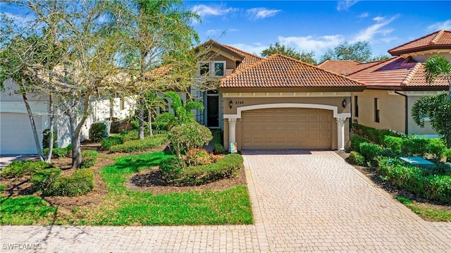 view of front of house featuring decorative driveway, an attached garage, a tile roof, and stucco siding