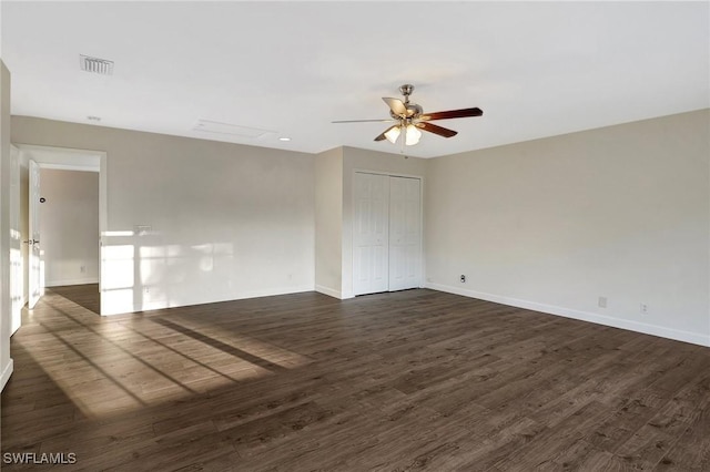 unfurnished room with dark wood-style floors, visible vents, baseboards, and a ceiling fan