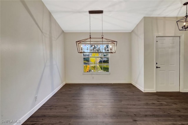 unfurnished dining area featuring a chandelier, dark wood-type flooring, and baseboards