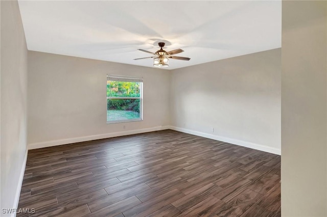 spare room with dark wood-type flooring, a ceiling fan, and baseboards