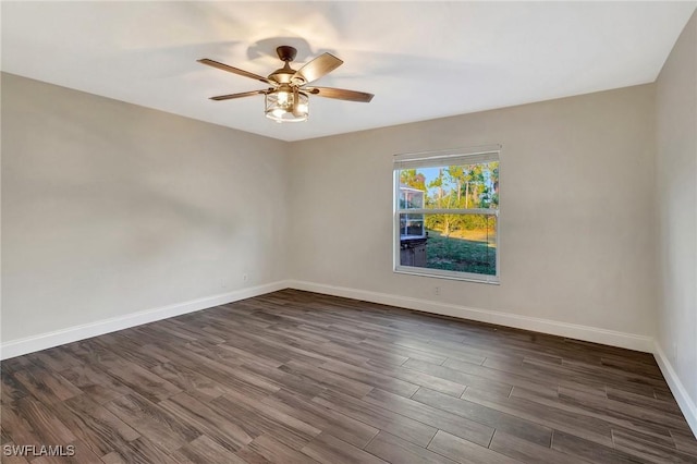 empty room featuring dark wood-style floors, a ceiling fan, and baseboards