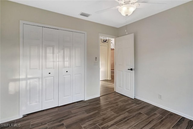 unfurnished bedroom with dark wood-type flooring, a closet, visible vents, and baseboards