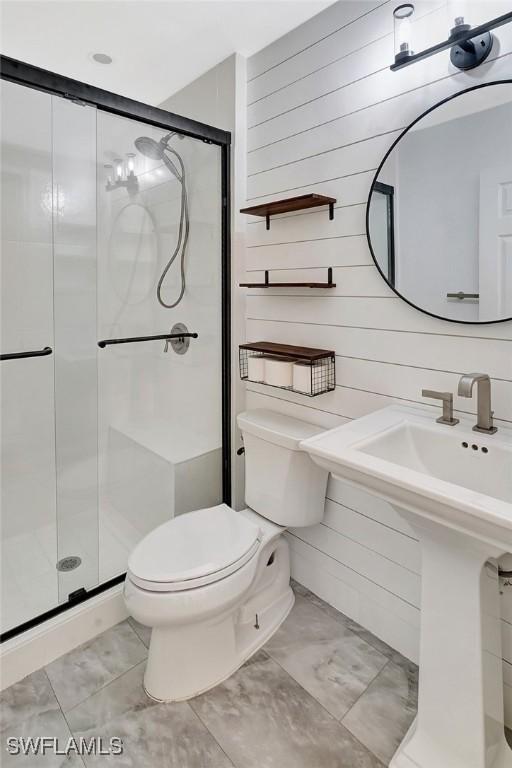 bathroom featuring wood walls, a stall shower, and toilet