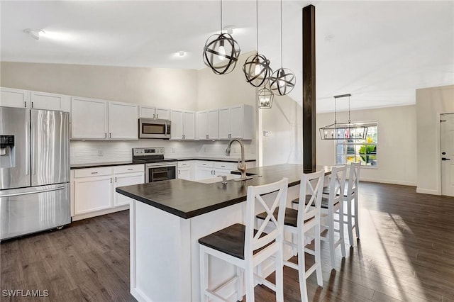 kitchen featuring dark countertops, white cabinets, stainless steel appliances, and decorative light fixtures