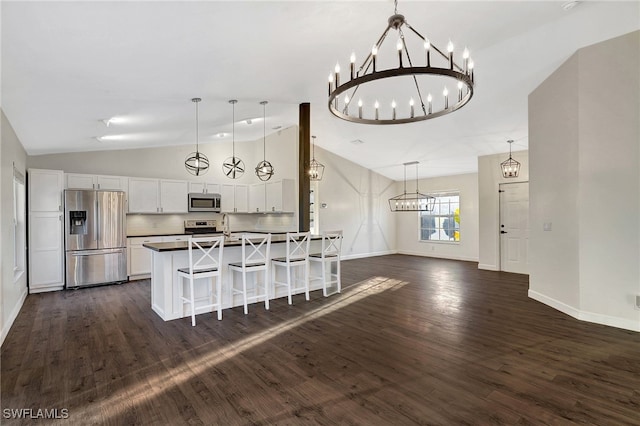 kitchen with dark countertops, white cabinetry, appliances with stainless steel finishes, and hanging light fixtures