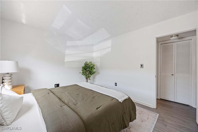 bedroom with a textured ceiling, baseboards, and wood finished floors