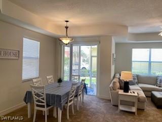 dining space featuring baseboards, dark carpet, and a tray ceiling