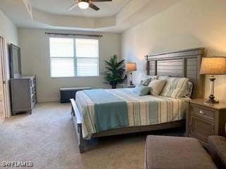 bedroom with a tray ceiling, light carpet, and ceiling fan