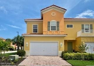 view of front of property with decorative driveway, an attached garage, and stucco siding