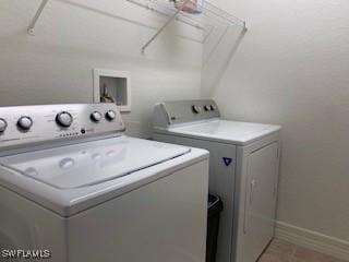 laundry room featuring laundry area, washer and clothes dryer, baseboards, and light tile patterned floors