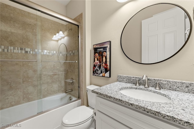 bathroom featuring toilet, combined bath / shower with glass door, and vanity