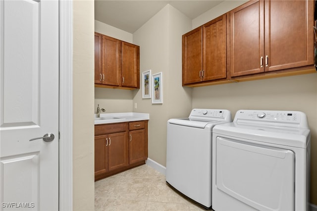 laundry room with light tile patterned flooring, a sink, baseboards, cabinet space, and washing machine and clothes dryer