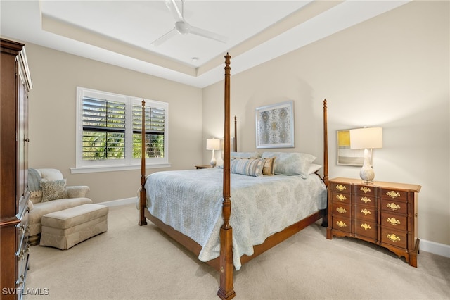 bedroom featuring a tray ceiling, light colored carpet, and baseboards