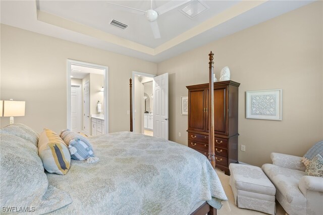 bedroom featuring a ceiling fan, visible vents, a tray ceiling, and connected bathroom