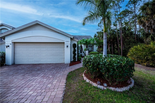 ranch-style home with an attached garage, decorative driveway, and stucco siding