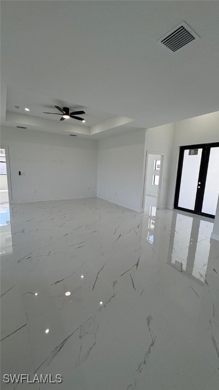 unfurnished room featuring visible vents, ceiling fan, marble finish floor, a tray ceiling, and french doors