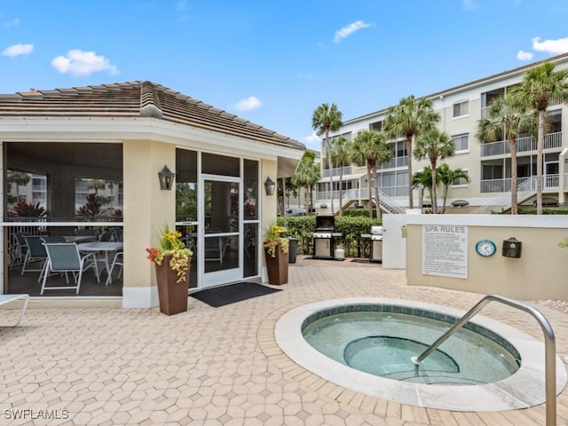 view of swimming pool featuring a patio area, a community hot tub, and area for grilling