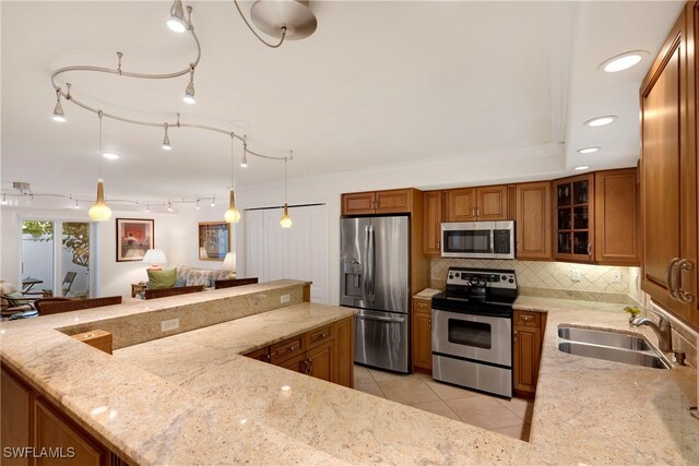 445 3rd Ave S Unit 102, Naples, FL 34102 - kitchen featuring appliances with stainless steel finishes, brown cabinets, decorative backsplash, light stone counters, and recessed lighting