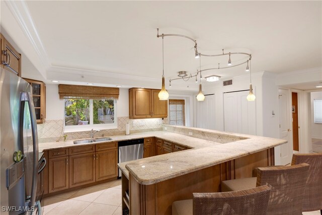 445 3rd Ave S Unit 102, Naples, FL 34102 - kitchen featuring appliances with stainless steel finishes, a peninsula, decorative backsplash, light stone countertops, and a kitchen bar