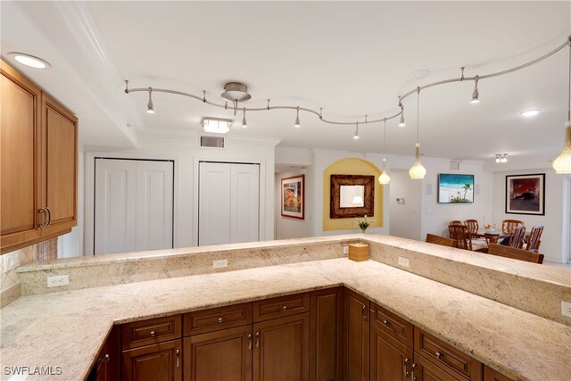 445 3rd Ave S Unit 102, Naples, FL 34102 - kitchen with light stone counters, crown molding, brown cabinetry, and a peninsula