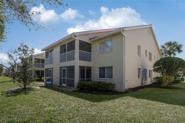rear view of property with stucco siding and a yard