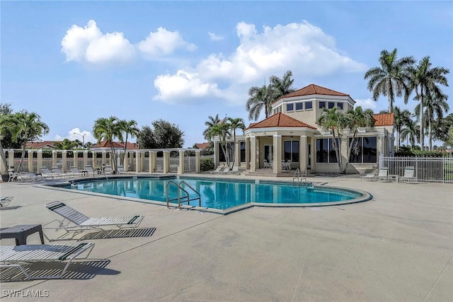 community pool with a patio area and fence