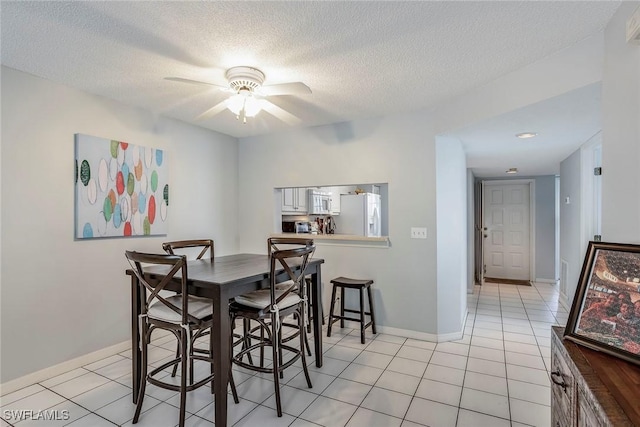 dining room with light tile patterned floors, baseboards, a textured ceiling, and a ceiling fan