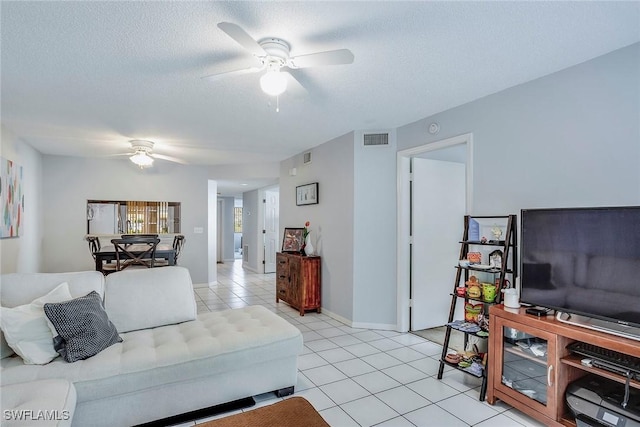 living area with visible vents, a textured ceiling, light tile patterned flooring, and a ceiling fan