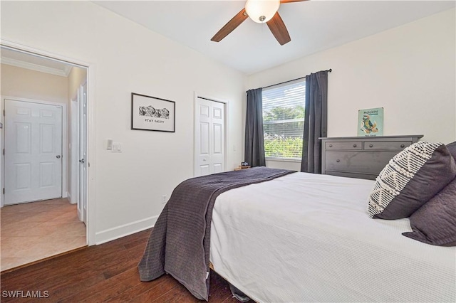 bedroom with a closet, dark wood-style flooring, ceiling fan, and baseboards