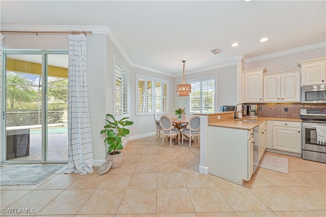 kitchen with light tile patterned flooring, a peninsula, a sink, hanging light fixtures, and appliances with stainless steel finishes