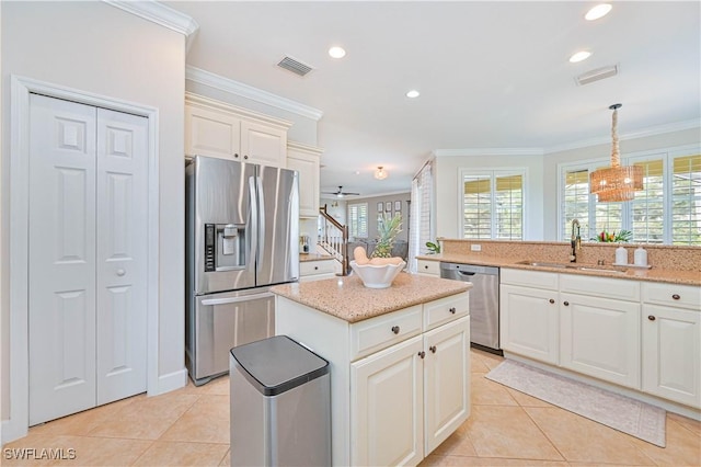 kitchen with pendant lighting, light tile patterned floors, appliances with stainless steel finishes, ornamental molding, and a sink