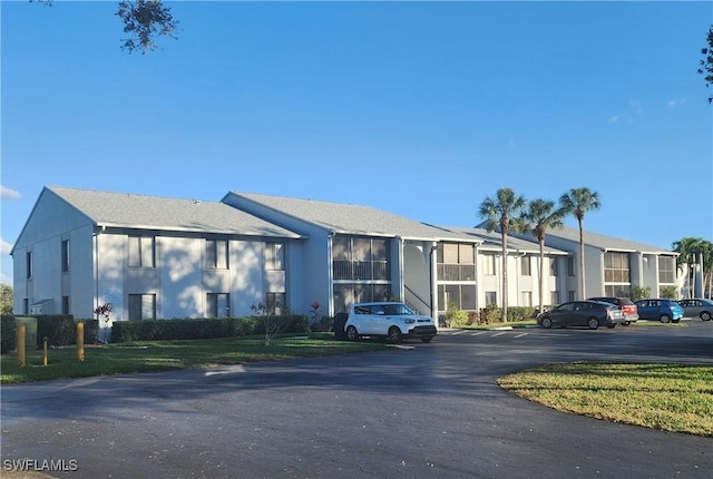 view of building exterior with uncovered parking and a residential view