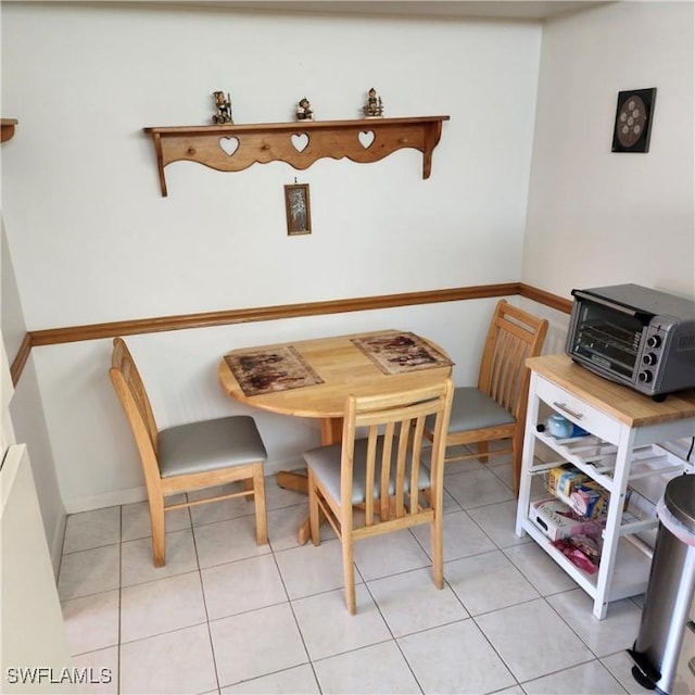 dining area featuring light tile patterned floors and a toaster