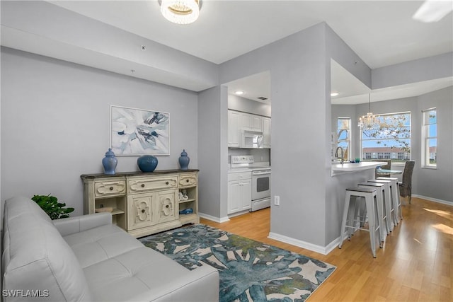 living room featuring recessed lighting, light wood-style floors, baseboards, and an inviting chandelier