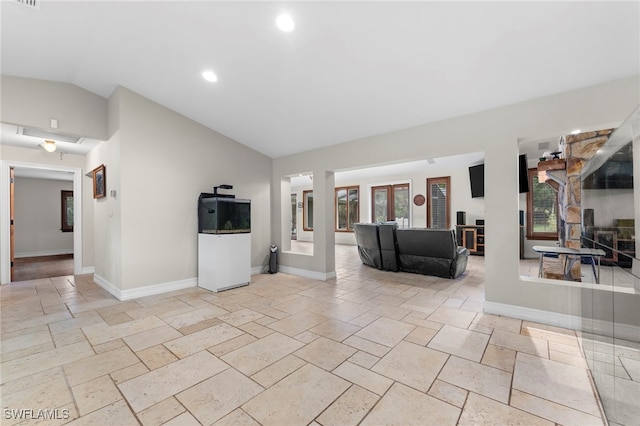 unfurnished living room featuring lofted ceiling, recessed lighting, baseboards, french doors, and stone tile flooring