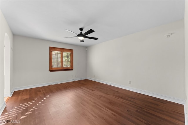 unfurnished room featuring a ceiling fan, arched walkways, baseboards, and wood finished floors