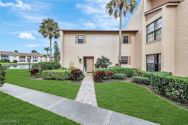 view of front of home featuring a water view, stucco siding, and a front yard